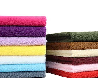 May include: Stacks of colorful, textured fabric in shades of pink, purple, yellow, blue, and gray on the left, and green, brown, cream, burgundy, pink, and red on the right. The fabric has a soft, fluffy appearance.