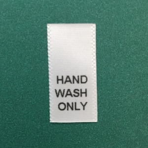 May include: White fabric care label with black text that reads "HAND WASH ONLY".