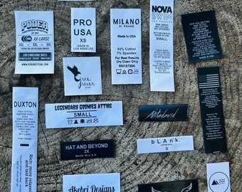May include: A collection of clothing labels with various brand names, sizes, and care instructions. The labels are printed on white paper with black ink and feature a variety of fonts and designs.