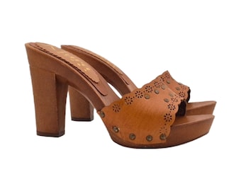 May include: A pair of brown leather platform clogs with high heels. The clogs feature a scalloped edge design with small circular cutouts and are adorned with small metal studs. The heels and platform are made of wood.