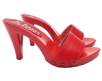 May include: Red leather heeled clogs with a pointed toe and a studded platform. The clogs have a small heel and a strap across the top of the foot. The brand name "Krava" is printed on the insole.