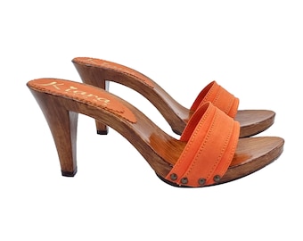 May include: A pair of orange suede heeled clogs with wooden soles and a gold logo that reads "Kiana" on the insole.