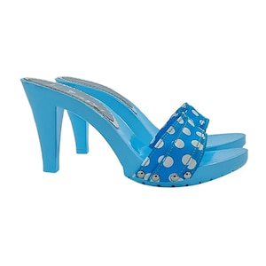 May include: A pair of light blue heeled clogs with a white polka dot pattern on the straps. The clogs have a high heel and a closed toe.