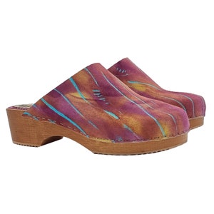May include: A pair of wooden clogs with a pink, orange, and blue tie-dye pattern. The clogs have a wooden heel and a closed toe.