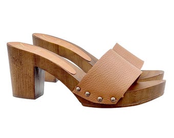 May include: Tan leather heeled clogs with a wooden platform and studded detail.