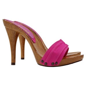 May include: A pair of wooden heeled clogs with a bright pink fabric strap. The strap has a decorative ruffle and is accented with silver studs.