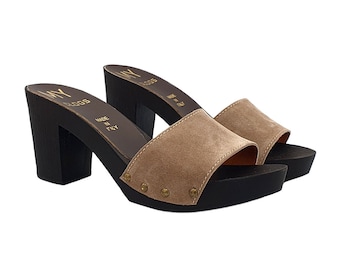 May include: A pair of beige suede heeled clogs with a black wooden platform and gold studs. The clogs are made in Italy and have a slip-on design.