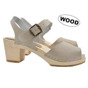 May include: Beige leather heeled sandals with a wooden platform and a buckle closure. The sandals have a peep toe and a closed back. The text "WOOD" is written on a white oval.