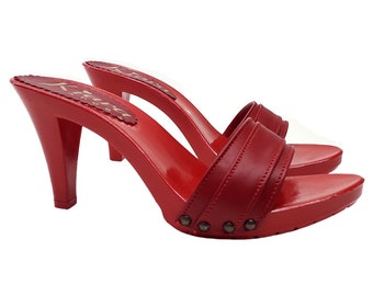 Könnte beinhalten: Ein Paar rote Holz-Sandalen mit Absatz, Lederriemen und Metallnieten. Die Sandalen haben einen hohen Absatz und eine geschlossene Zehenpartie.