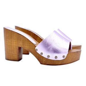 Puede incluir: Un par de zuecos de tacón de cuero lila con plataformas de madera y un detalle de tachuelas alrededor del borde superior.