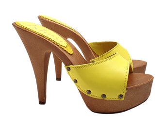 May include: Yellow leather platform clogs with a wooden heel and platform. The clogs have a pointed toe and a small buckle on the side.