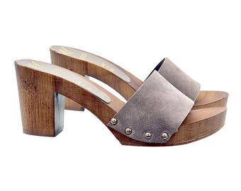May include: A pair of gray suede heeled clogs with wooden platforms and heels. The clogs have gold-toned studs around the edges of the straps.