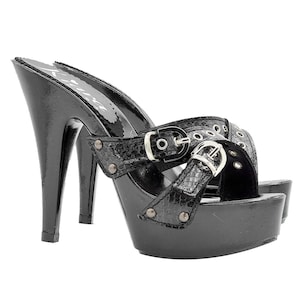 Könnte beinhalten: Schwarze Plateau-Sandalen mit Schnallenriemen und Schlangenhautmuster. Die Sandalen haben einen hohen Stiletto-Absatz und eine Plateau-Sohle.