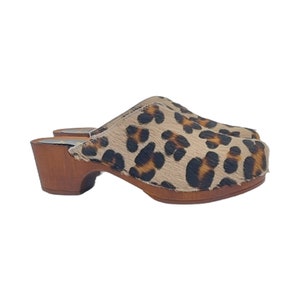 May include: Leopard print clogs with a wooden heel and a brown sole.