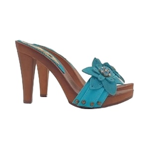 May include: Turquoise blue suede clogs with a wooden platform and heel. The clogs have a flower embellishment with rhinestones on the front strap.