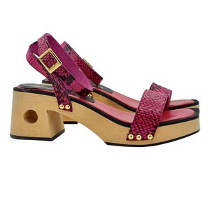 May include: Pink snakeskin heeled sandals with a wooden platform and gold accents.