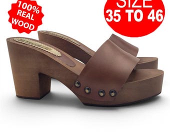 May include: Brown wooden clogs with a platform sole and a block heel. The upper is made of brown leather. The clogs have metal studs and the text "100% REAL WOOD" and "SIZE 35 TO 46" in the image.