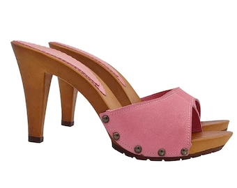 Könnte beinhalten: Rosa Wildledersandalen mit Holzplattform und hohem Absatz. Die Sandalen haben eine spitze Zehenpartie und sind mit kleinen Metallnieten verziert.