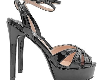 May include: Black platform sandals with a high stiletto heel and an ankle strap. The sandals have a knotted design on the toe strap.