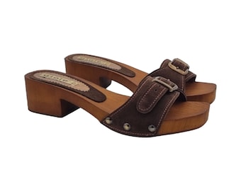 May include: Brown suede heeled clogs with a buckle closure and wooden platform. The clogs have a brown suede strap with a silver buckle and a wooden heel.