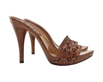 Könnte beinhalten: Braune Leder-Clogs mit Absatz und ausgeschnittenem Blumenmuster. Die Clogs haben einen hohen Absatz und eine Holzplattform.