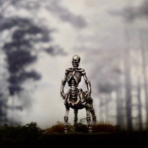 Peut inclure: Une figurine de centaure squelettique debout dans un décor de forêt brumeuse. La figurine est en métal et présente une structure squelettique détaillée.