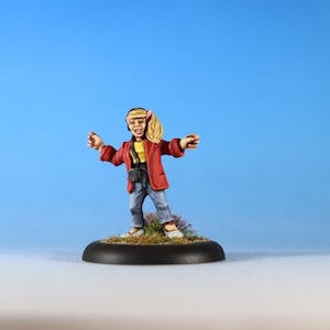 May include: A painted miniature figurine of a person wearing a red jacket, yellow shirt, blue jeans, and a headband. The figurine is standing on a black base with green foliage.
