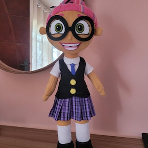 May include: A plush toy doll wearing a pink and white striped hat, black framed glasses, a white shirt with a blue tie, a black waistcoat with yellow buttons, a purple and black plaid skirt, white socks, and black shoes.