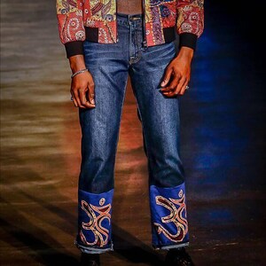 May include: Blue denim jeans with embroidered blue and gold trim at the bottom of the legs.