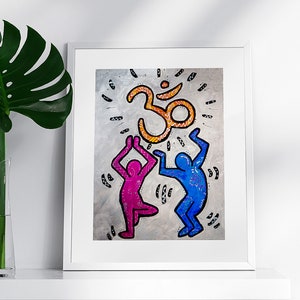May include: A framed print of a colourful illustration featuring two figures dancing with an orange Om symbol above them. The background is a grey textured surface.