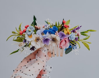 Könnte beinhalten: Ein bunter Blumenhaarkamm mit einer Vielzahl von Blumen, darunter rosa, blaue, lila und weiße. Der Kamm ist aus goldenem Metall gefertigt und hat ein filigranes Design.