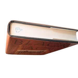 May include: A hardcover book titled "BLACK SAGE" with a brown cover and white pages. The book has a blue hand-shaped bookmark. The title is in large, bold, white letters.