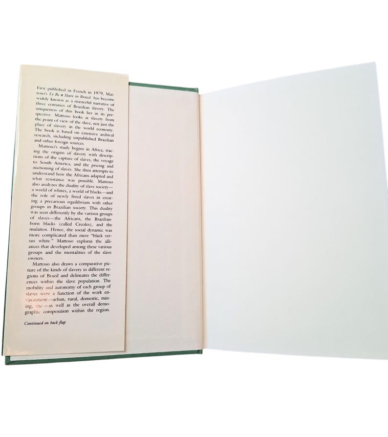 Puede incluir: Libro abierto con texto en la p&aacute;gina izquierda y una p&aacute;gina derecha en blanco. El texto describe la historia de la esclavitud en Brasil. El libro tiene una cubierta verde y un marcador blanco. El texto incluye la frase "First published in French in 1979."