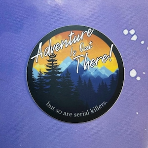 May include: A round sticker with a mountain scene and the text "Adventure is Out There! but so are serial killers."