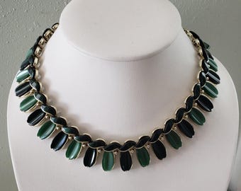 May include: A necklace featuring a series of alternating black and dark green oval-shaped cabochon stones set in gold-tone metal links. The stones are arranged in a repeating pattern along the entire length of the collar-style necklace.