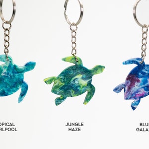 May include: Three turtle-shaped keychains with different marbled patterns: Tropical Whirlpool (blue and green), Jungle Haze (green and yellow), and Blue Galaxy (blue and purple).