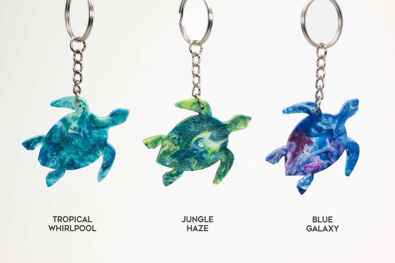 May include: Three turtle-shaped keychains with different marbled patterns: Tropical Whirlpool (blue and green), Jungle Haze (green and yellow), and Blue Galaxy (blue and purple).
