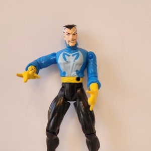 May include: A blue and white action figure of Doctor Strange with a yellow belt and black pants. The figure has a serious expression on its face.
