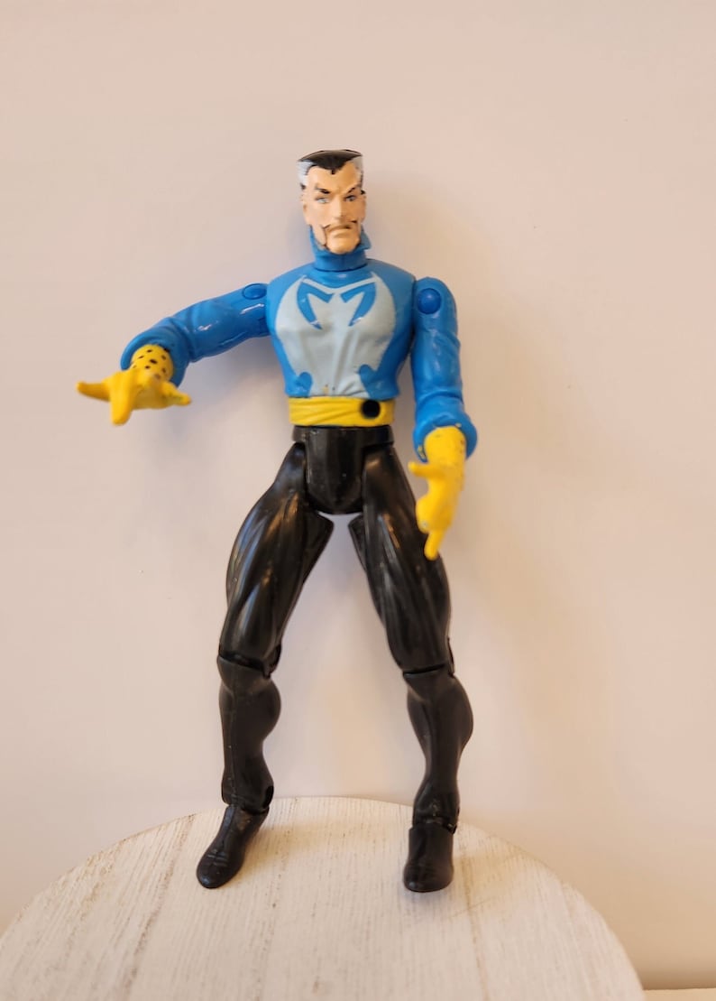 May include: A blue and white action figure of Doctor Strange with a yellow belt and black pants. The figure has a serious expression on its face.