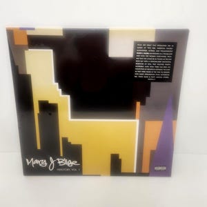 May include: A vinyl record album titled "Herstory, Vol. 1" by Mary J. Blige. The album cover features a geometric design with black, yellow, orange, and purple shapes. The album has a parental advisory sticker.