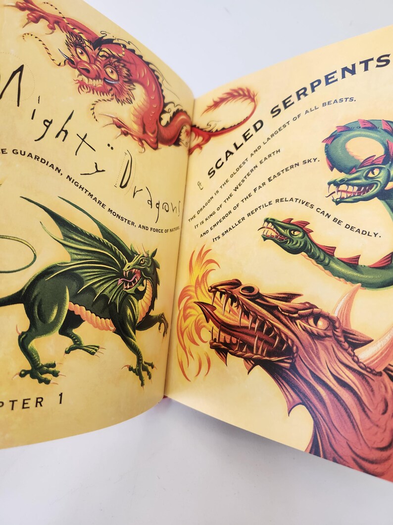 May include: An open book page featuring illustrations of dragons with text reading Mighty Dragons, Chapter 1, Scaled Serpents, The dragon is the oldest and largest of all beasts, It is king of the western earth and emperor of the far eastern sky.