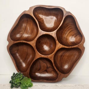 May include: A vintage wooden serving tray with seven compartments. The tray is a warm brown color with a natural wood grain pattern. The compartments are various organic shapes, perfect for serving snacks or appetizers.
