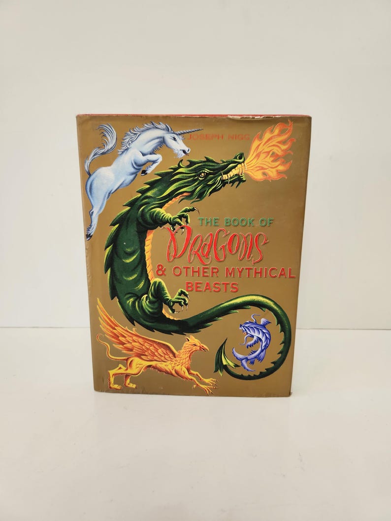 May include: A hardcover book titled The Book of Dragons & Other Mythical Beasts by Joseph Nigg. The gold cover features a white unicorn, a large green dragon breathing orange fire, a golden winged griffin, and a small blue sea creature.