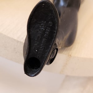 May include: Close-up of the bottom of a black plastic action figure leg. The bottom of the leg has a hole and the text "&copy;1983 Mattel, Inc."