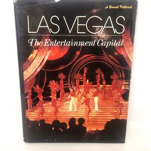 May include: A vintage book cover with the title "LAS VEGAS" and the subtitle "The Entertainment Capital." The cover features a stage performance with dancers in red costumes. The book is a Sunset Pictorial.