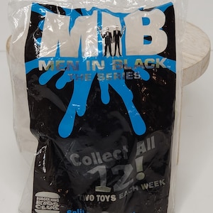 May include: Sealed Burger King Kids Club toy from the Men in Black: The Series collection. The plastic packaging features the MIB logo, blue splatter design, and the text "Collect All 12!" and "Two Toys Each Week."