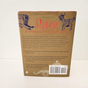 May include: The back cover of a gold-toned book titled The Book of Dragons & Other Mythical Beasts. It features blue line illustrations of a lion and a donkey-like creature, descriptive text, bullet points, and a barcode with ISBN 1-901412-17-0.