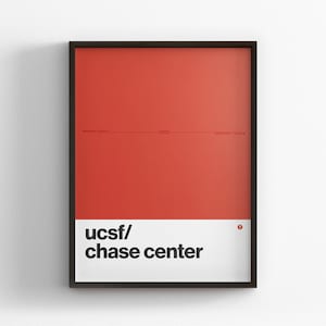 May include: A framed rectangular wall art print featuring a solid red upper section and a white lower section. The text 'ucsf/ chase center' is printed in black on the white background. A thin black frame surrounds the entire print.