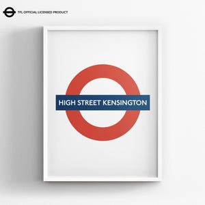 May include: A framed wall art print featuring the London Underground roundel logo in red and blue with the text HIGH STREET KENSINGTON in white capital letters. The top left corner includes the text TFL OFFICIAL LICENSED PRODUCT.