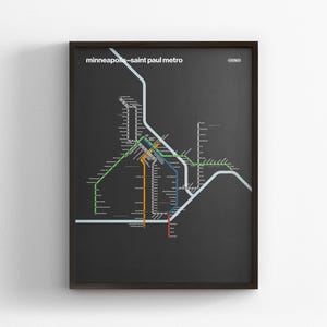 May include: Framed print of the Minneapolis-Saint Paul metro map. The map features a network of colorful lines on a dark gray background, with the text "minneapolis-saint paul metro" at the top. The frame is black.